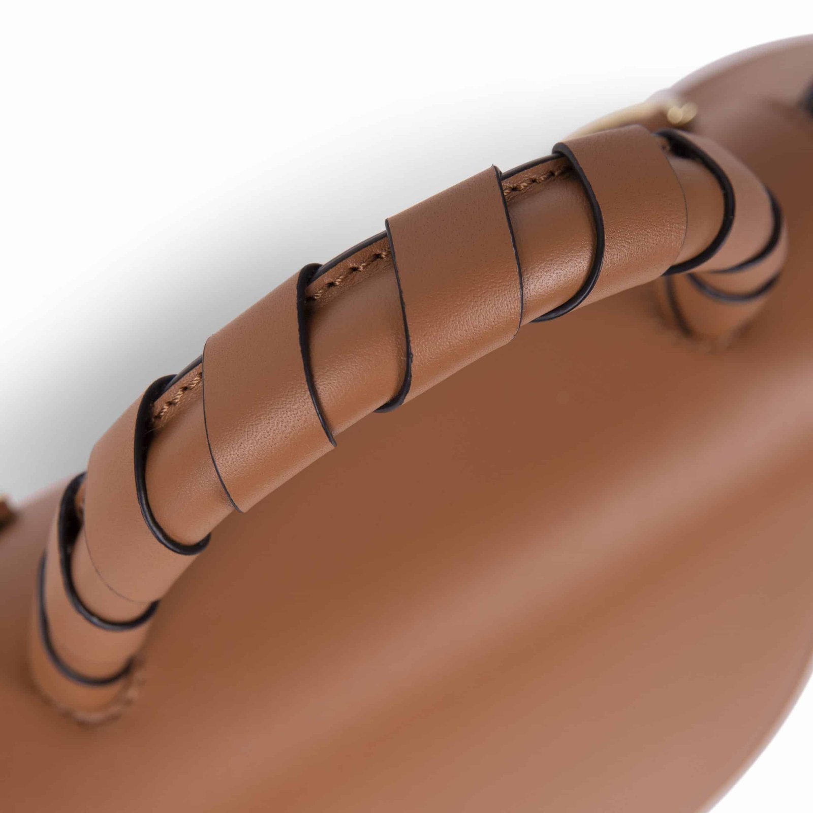 Detalle del asa trenzada en cuero marrón de un bolso Lauburu, con costuras precisas y acabado artesanal de lujo. Diseño exclusivo en marroquinería premium