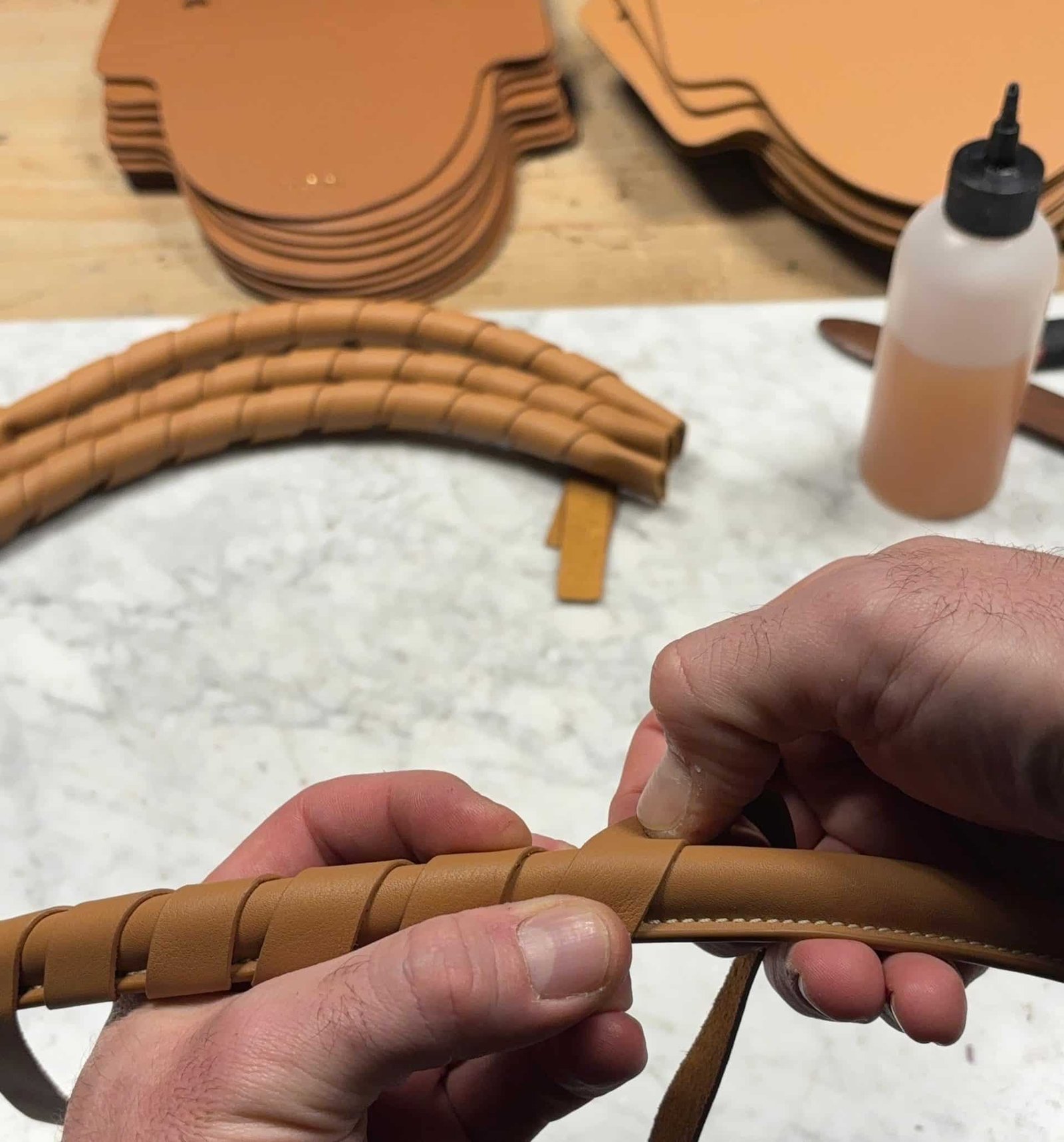 Artesano trabajando a mano en el trenzado de asas de cuero para bolsos Lauburu, en un proceso de marroquinería artesanal de alta calidad