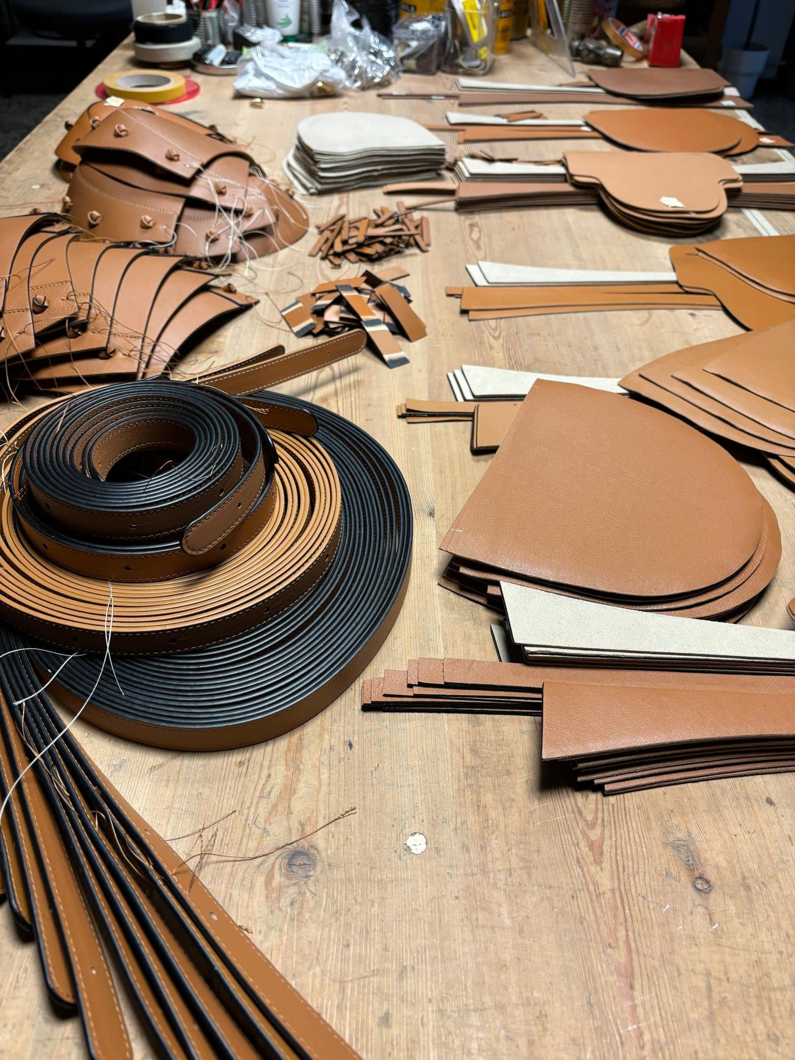 Materiales y piezas de cuero en proceso de fabricación artesanal de bolsos Lauburu. Producción de marroquinería de lujo con acabados detallados