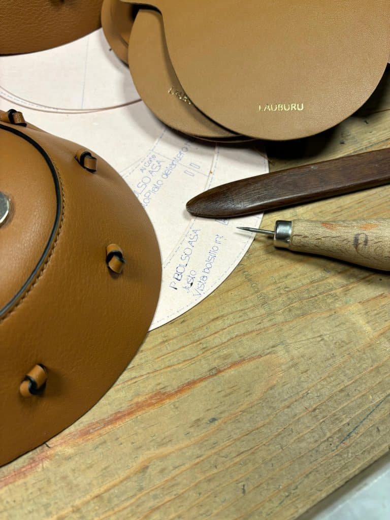 Proceso de fabricación artesanal de bolsos Lauburu: herramientas de marroquinería, patrones y piezas de cuero en desarrollo