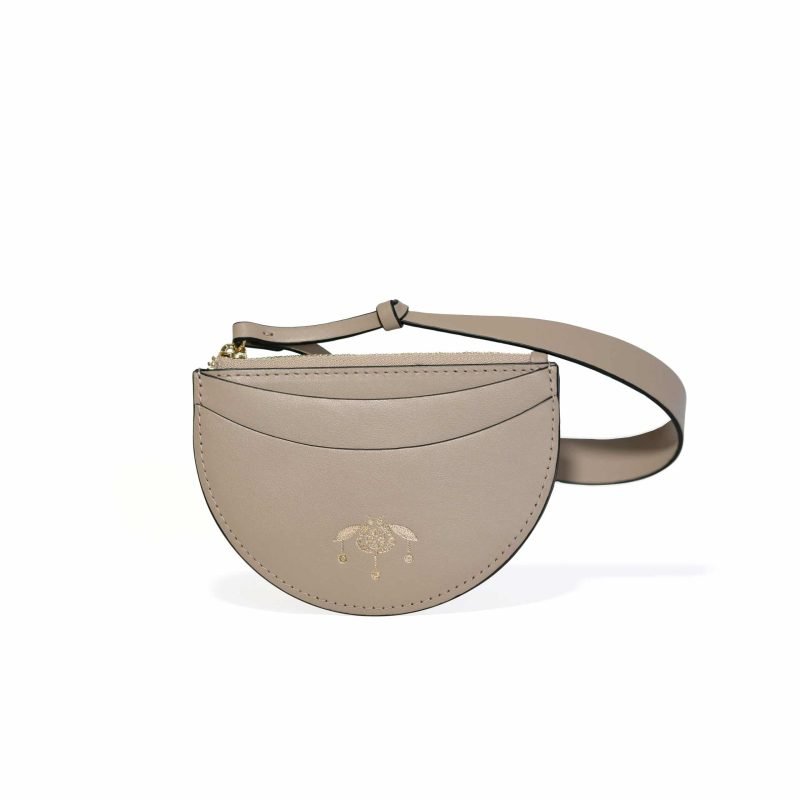 Tarjetero de piel color taupe Viviana de Lauburu con logo grabado en dorado. Diseño semicircular con costuras decorativas, correa ajustable y cierre de cremallera dorado, combinando elegancia y funcionalidad.